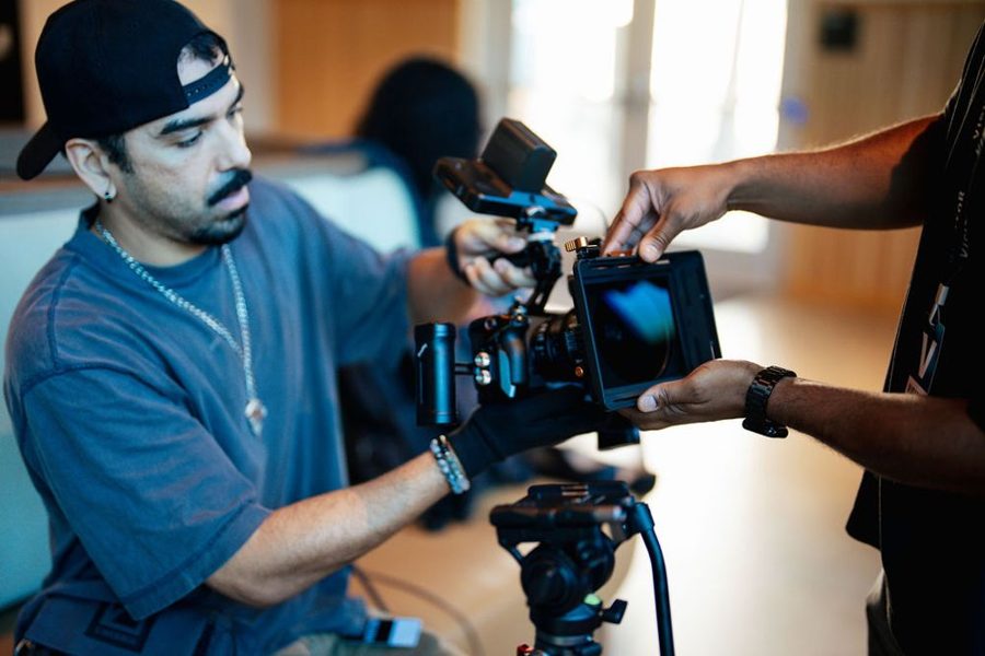 Two crew members building a cinema camera rig on a tripod
